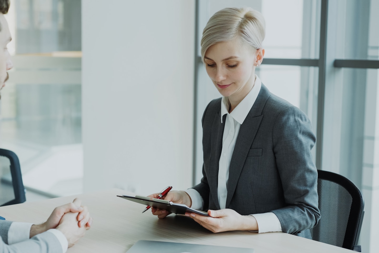 HR businesswoman having job interview with young man in suit and watching his resume application in modern office indoors