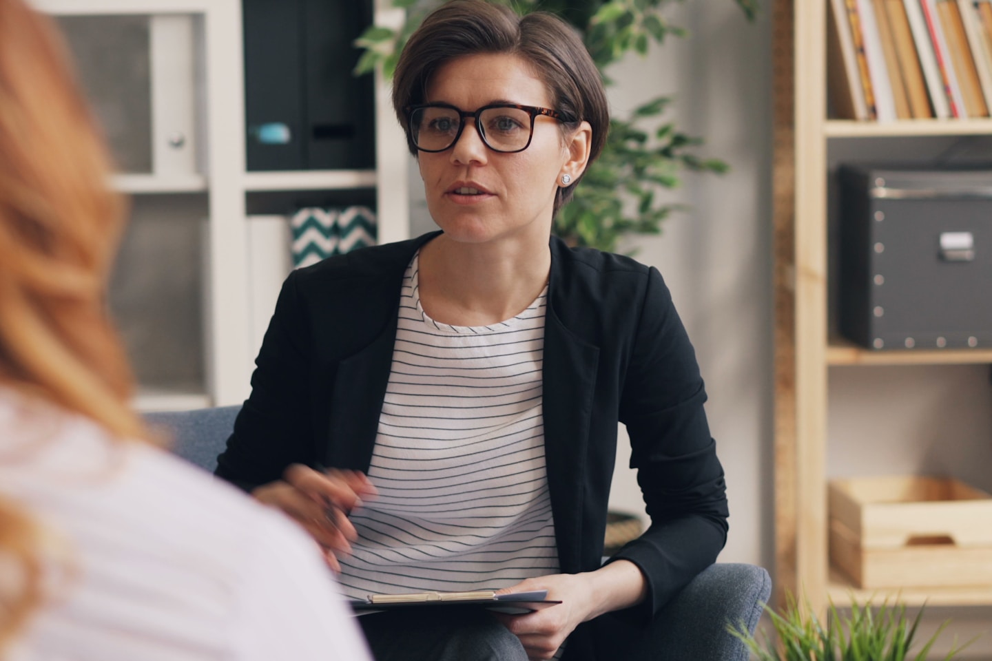 a woman sitting on a couch talking to another woman